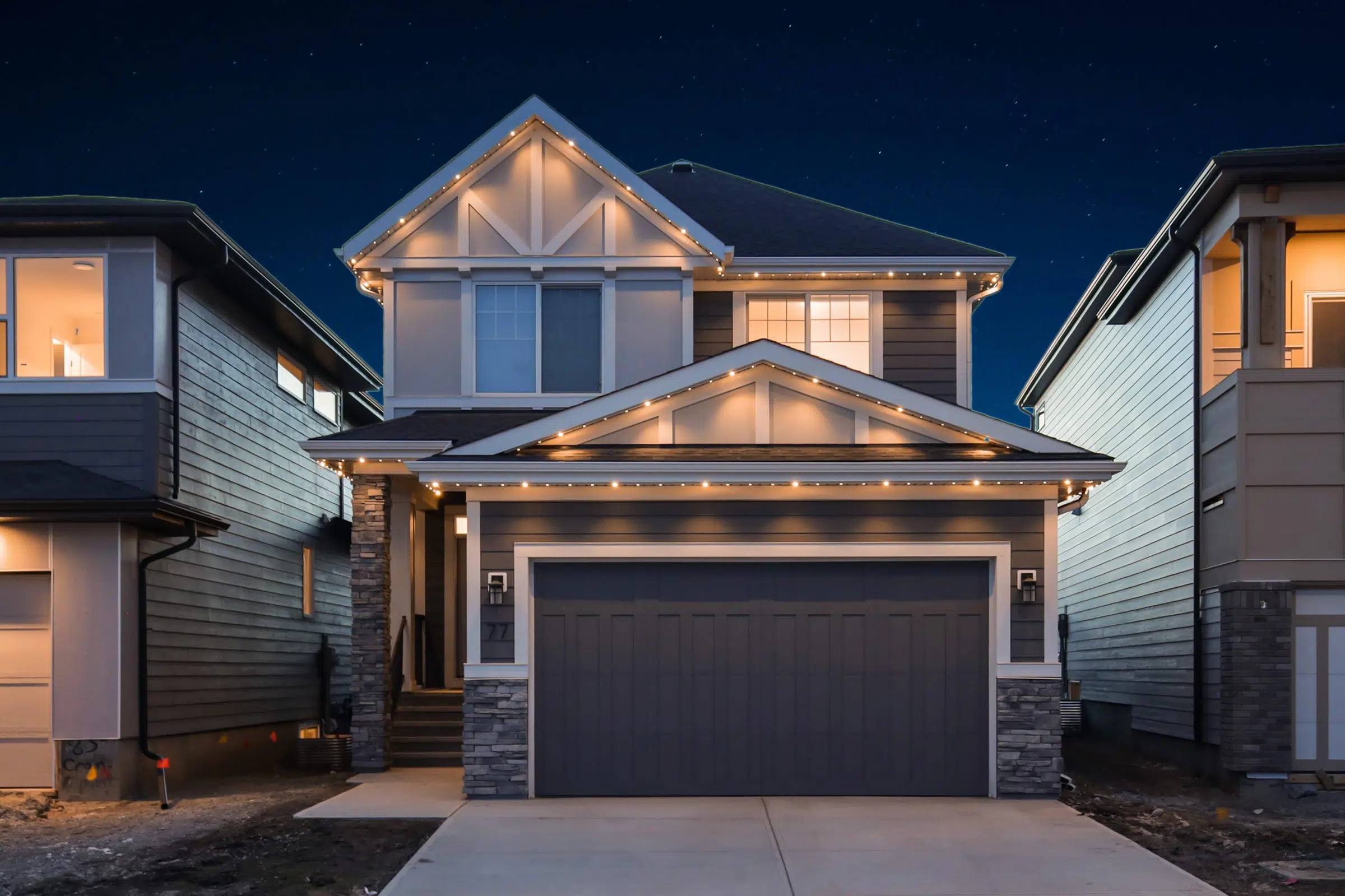 The same home with warm white Gemstone lights along every roofline