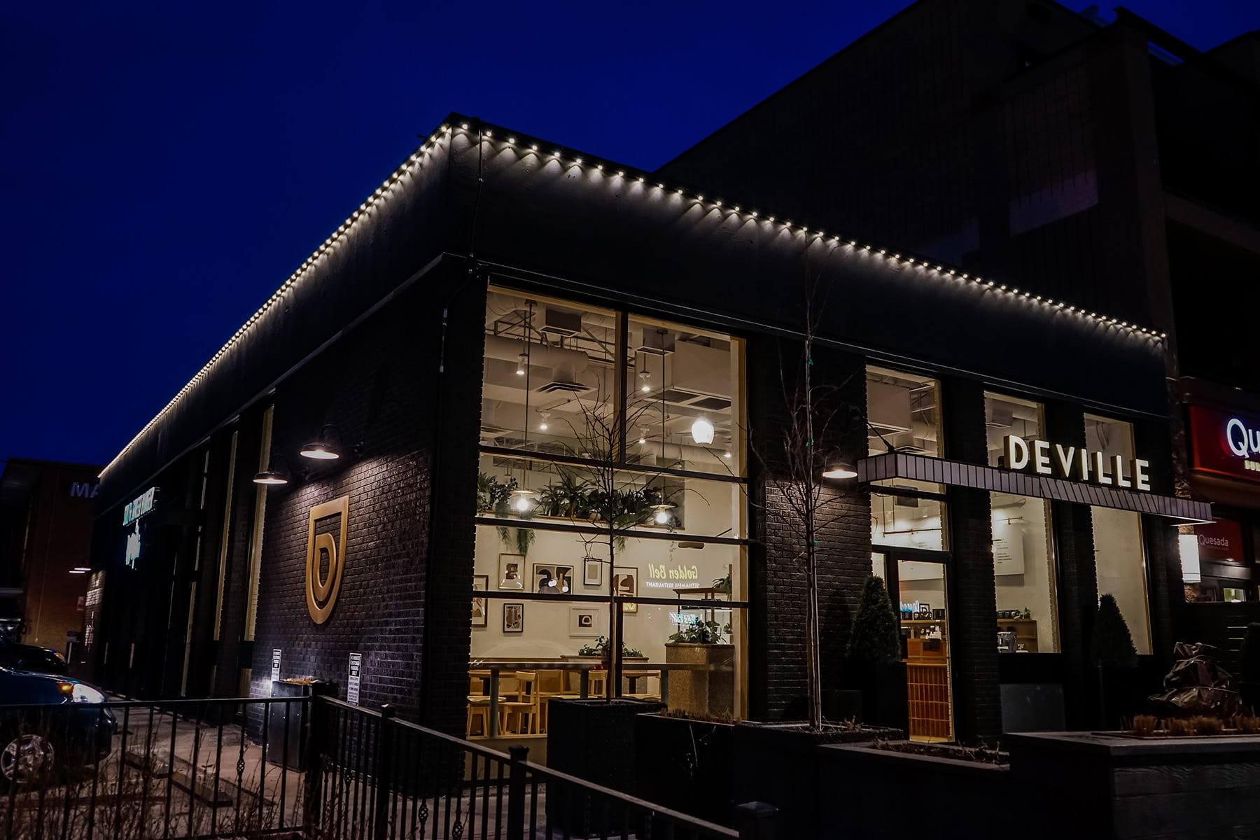Coffee shop with warm Gemstone lights along the roofline at night