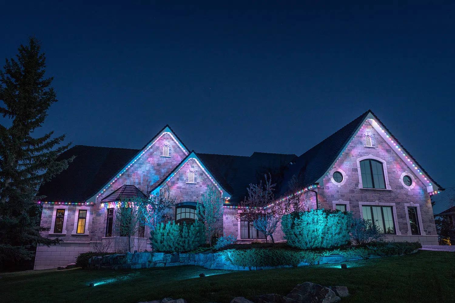 Home with teal and purple uplighting from Gemstone landscape lights