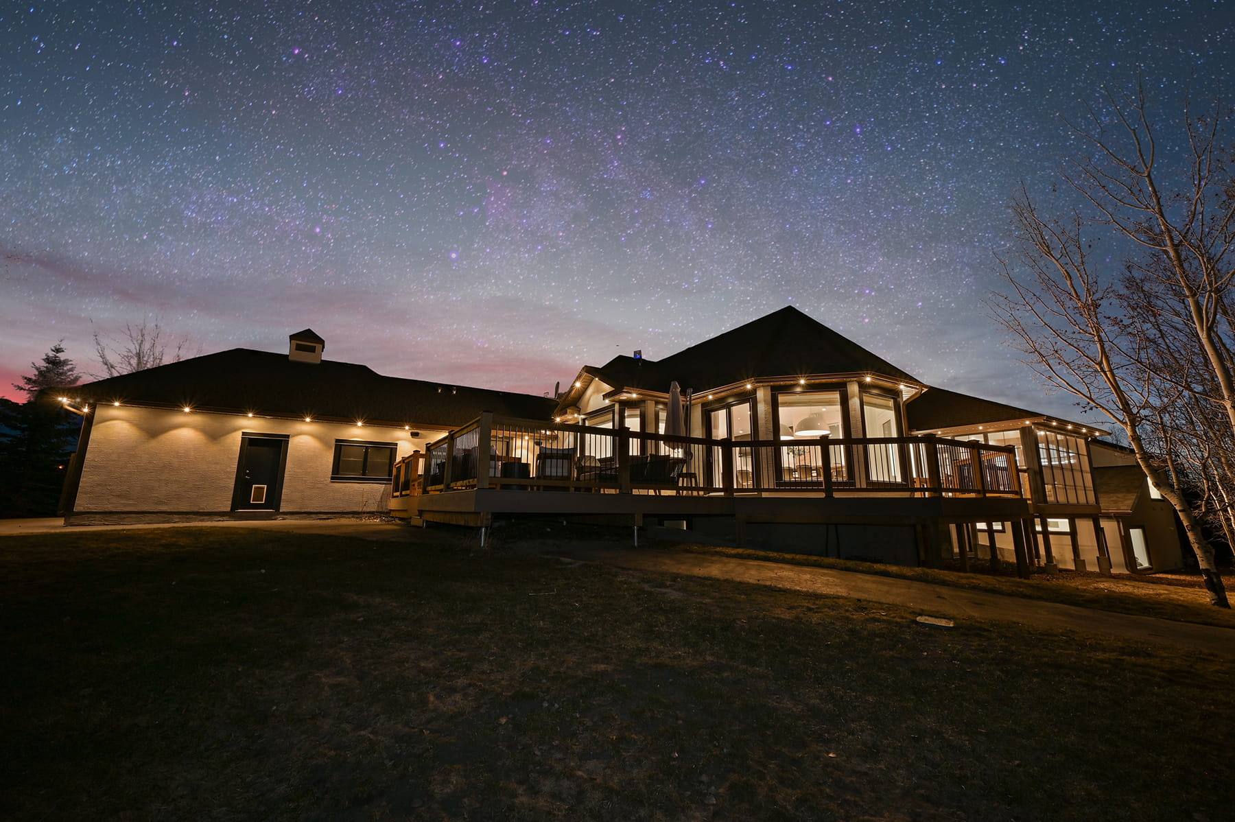 Ranch-style home with warm white Gemstone lights under a starry sky