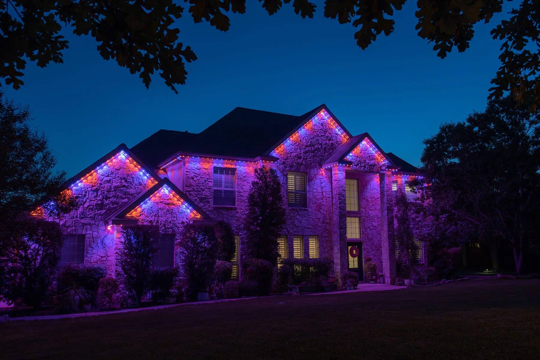Large stone home lit purple with Gemstone lights
