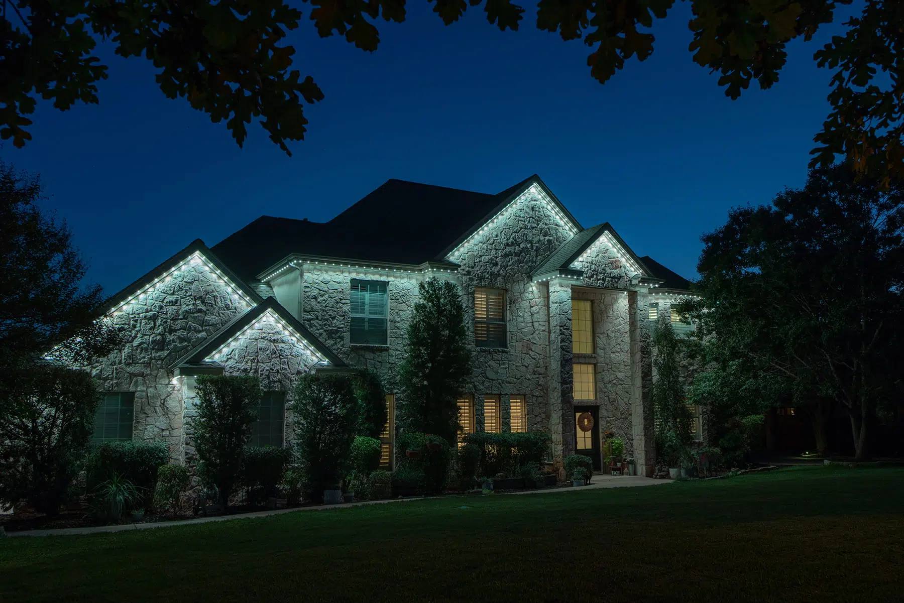 Large stone home lit with bright white Gemstone lights
