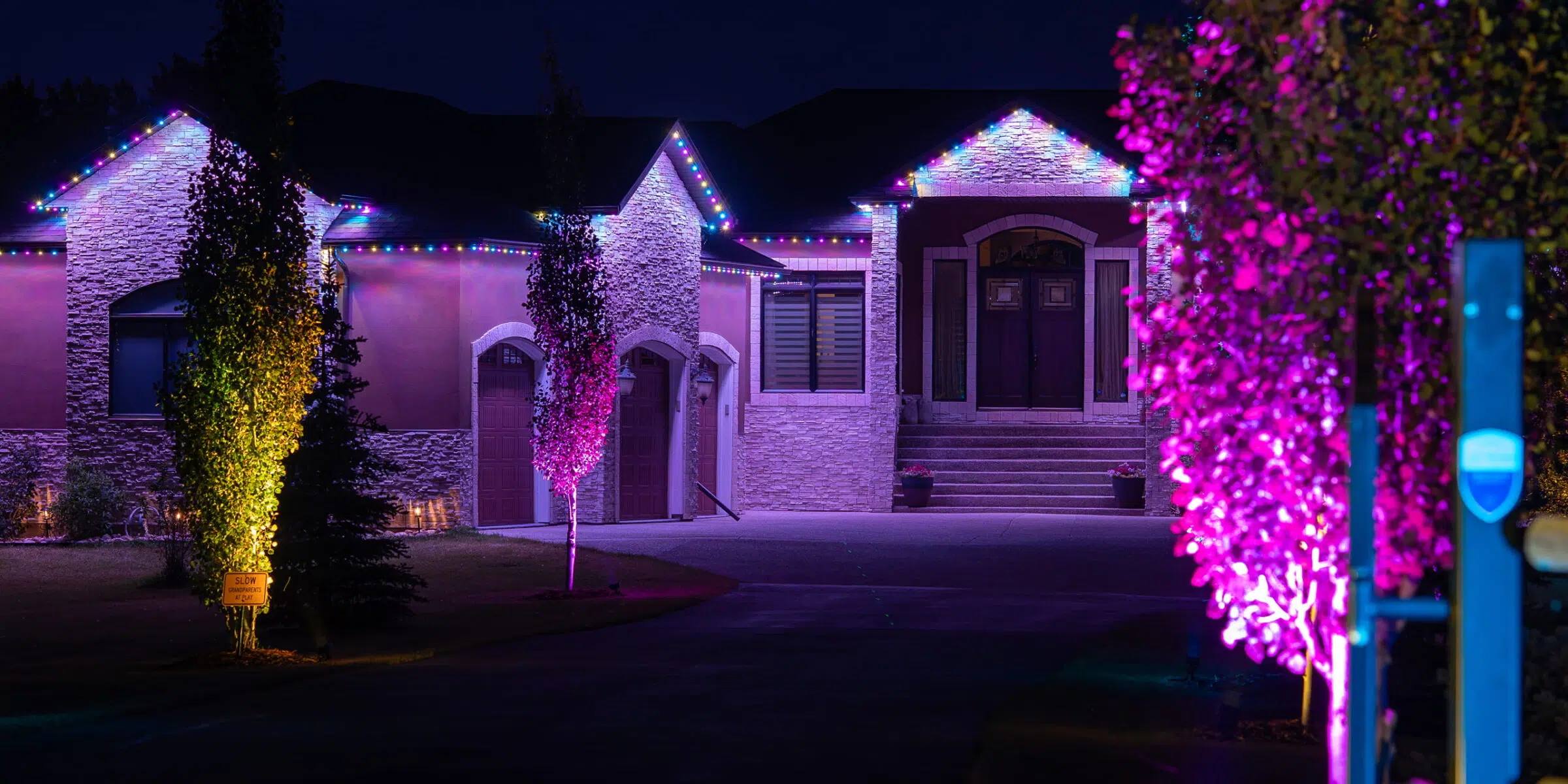 Home with trees uplit pink and purple